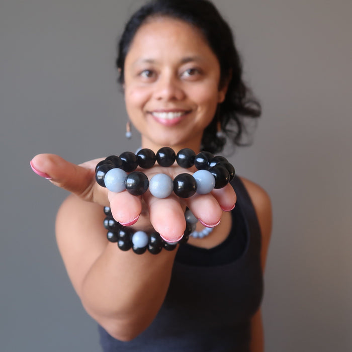 sheila of satin crystals extending her palm with a blue angelite and black rainbow obsidian stretch bracelet
