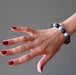 female hand modeling blue angelite and black rainbow obsidian stretch bracelet