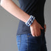 female hand in jeans pocket wearing a stack of lapis and angelite bracelets