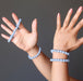 two hands wearing blue angelite round beaded stretch bracelets