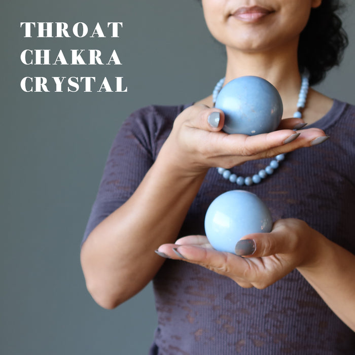 sheila of satin crystals holding two angelite spheres at the throat chakra