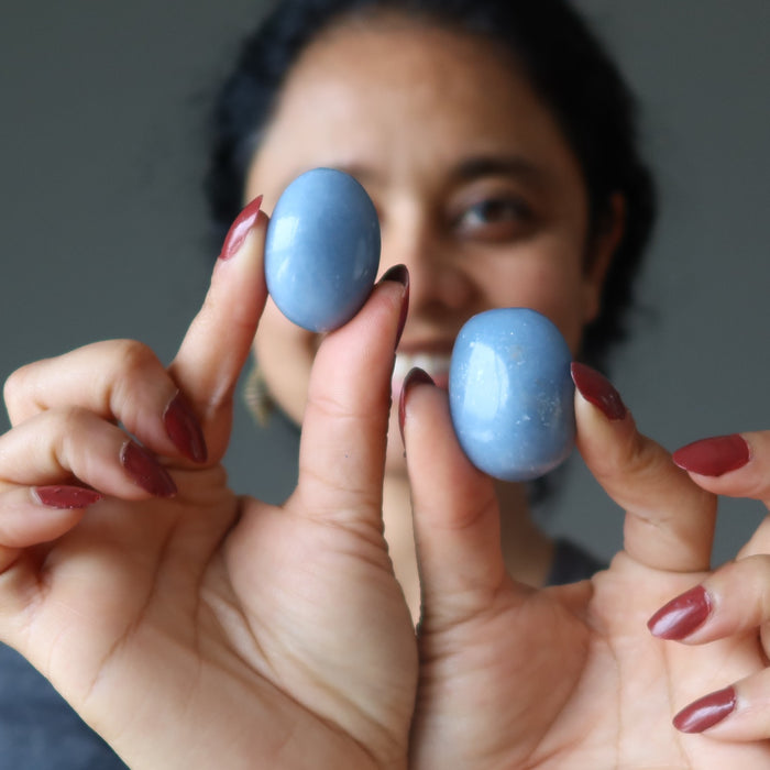 woman holding two angelite tumbled stones
