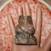 Rhodonite Owl Figurine laying on the mannequin's palm
