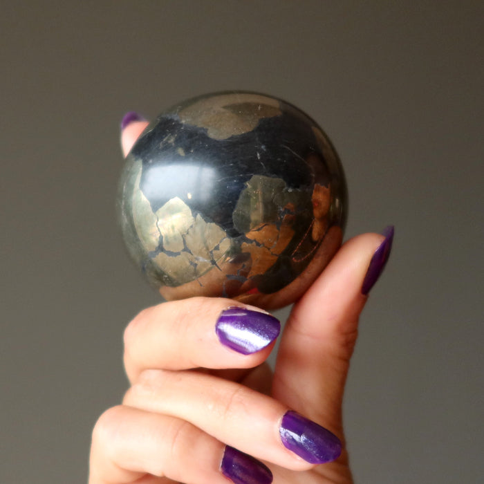 hand holding gold and black apache gold sphere