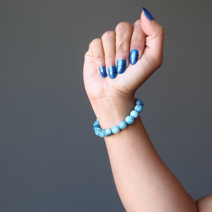hand making a fist wearing  blue apatite gemstone stretch bracelet