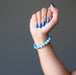 hand making a fist wearing  blue apatite gemstone stretch bracelet