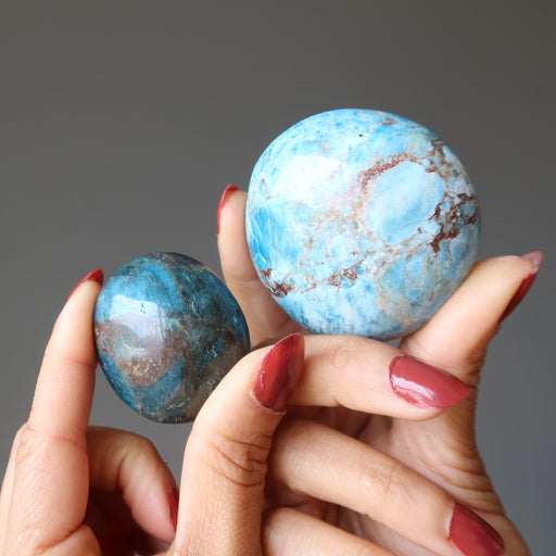 hands holding two rocky blue apatite palm stones