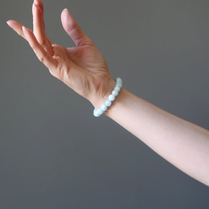 female hand modeling round blue-green aquamarine beaded stretch bracelet