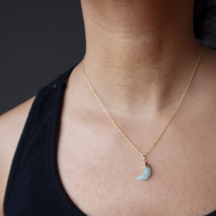 neck wearing aquamarine crescent moon pendant on gold necklace