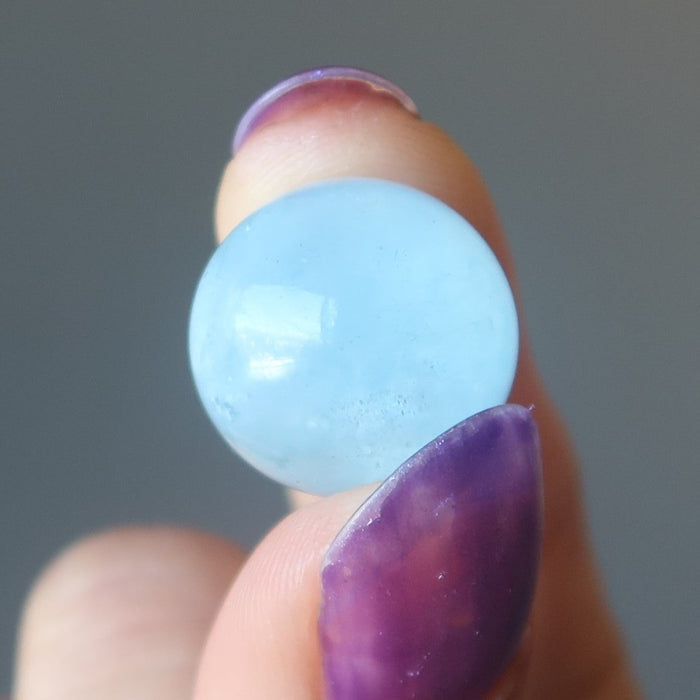hand holding blue aquamarine sphere