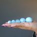 hand holding 5 blue aquamarine spheres
