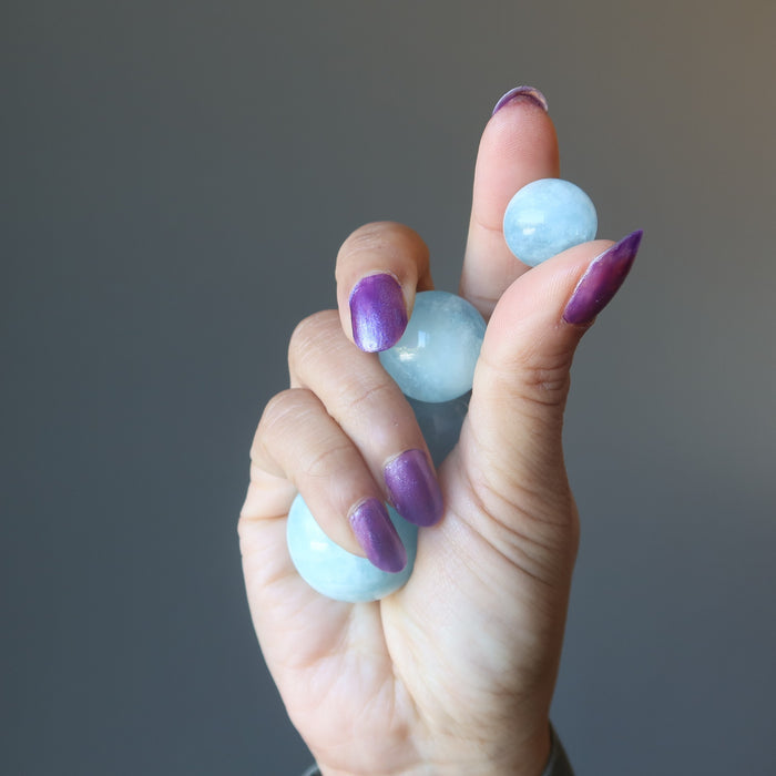 hand holding blue aquamarine spheres