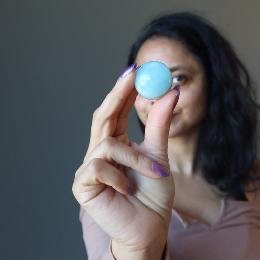 woman holding up blue aquamarine sphere