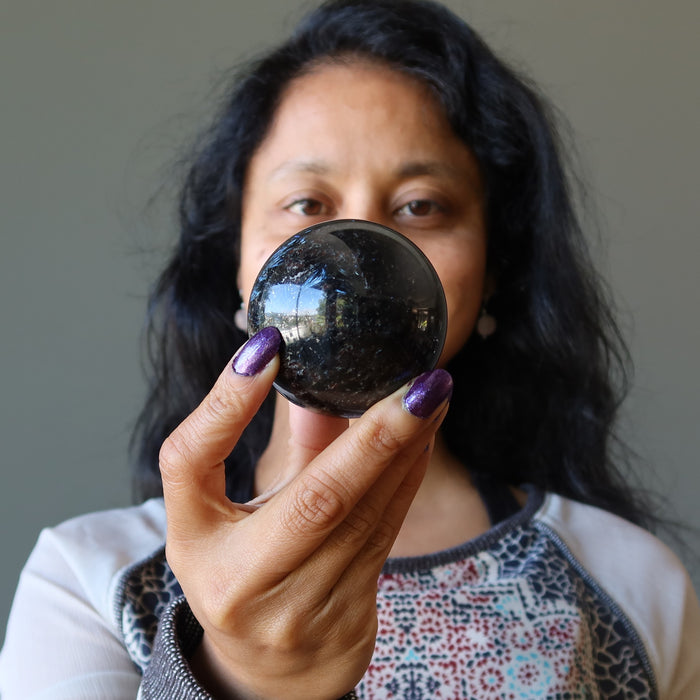 sheila of satin crystals holding an arfvedsonite sphere