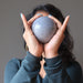 sheila of satin crystals holding a blue aventurine sphere in front of her face