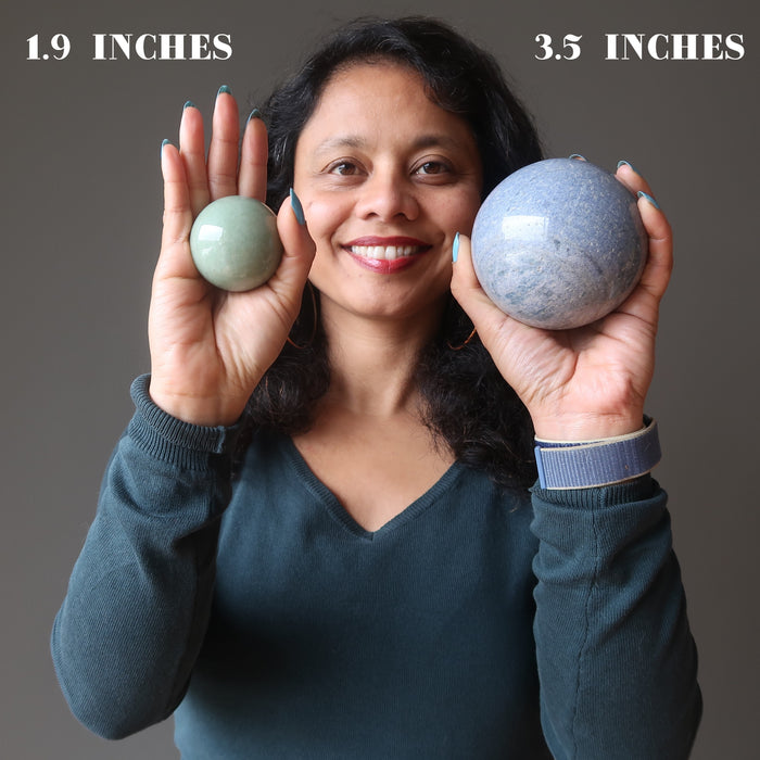 sheila of satin crystals holding a green aventurine and a blue aventurine sphere in each hand showing size differences
