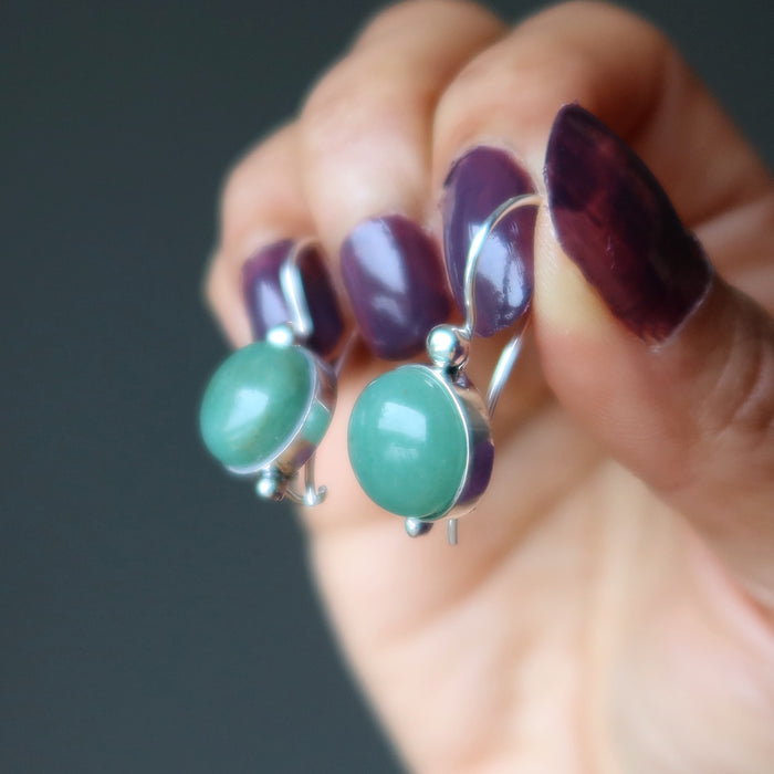 hands holding green aventurine circles in sterling silver earrings