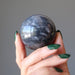 hand holding gray and white aventurine sphere