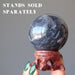 hand holding gray and white aventurine sphere on wood stand