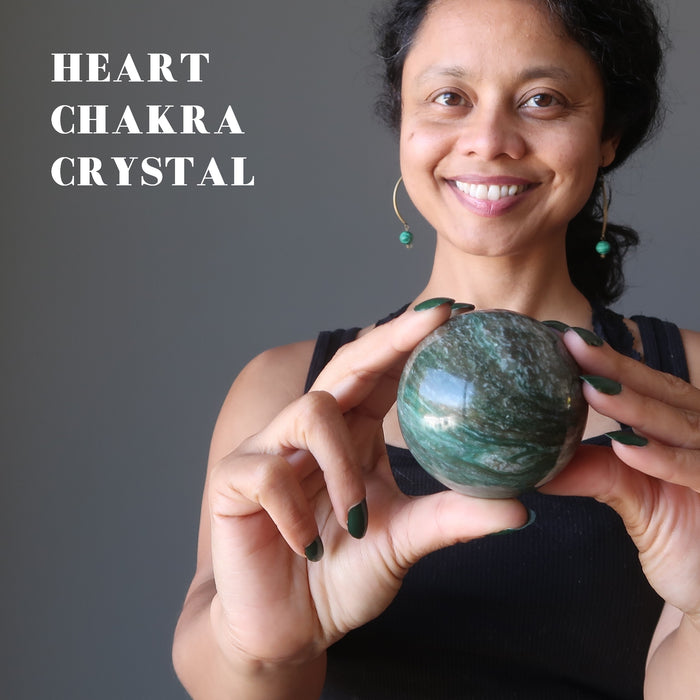 sheila of satin crystals holding green and white streaked aventurine sphere in front of her heart chakra