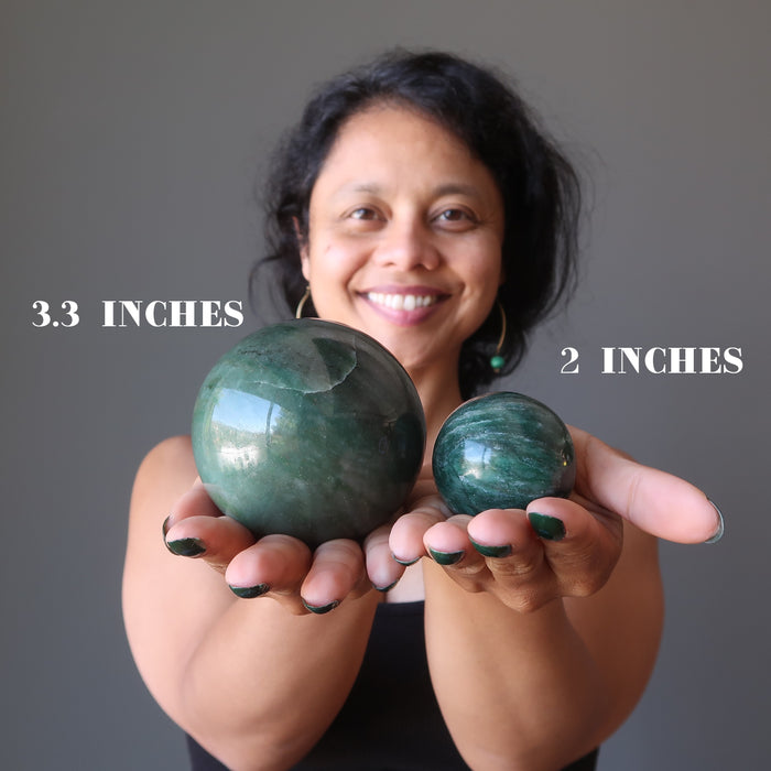 sheila of satin crystals holding green and white streaked aventurine spheres in her palms showing different size variations