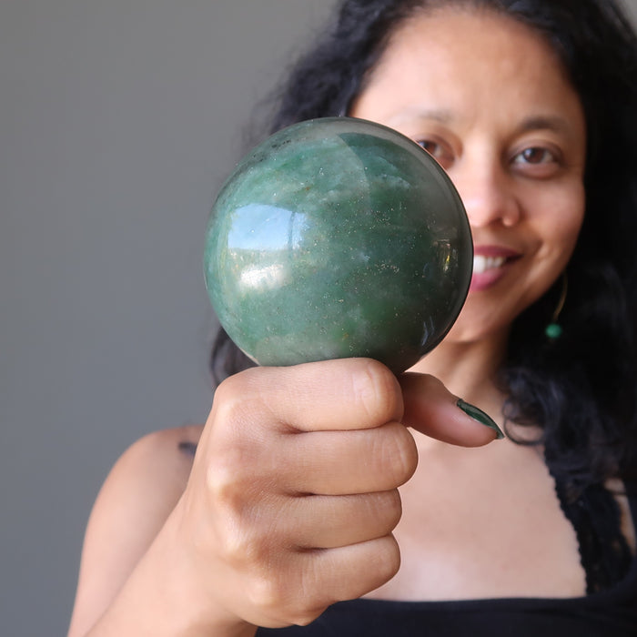sheila of satin crystals holding a green aventurine sphere on her fist