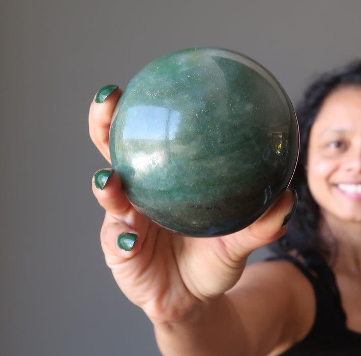 sheila of satin crystals holding a green aventurine sphere