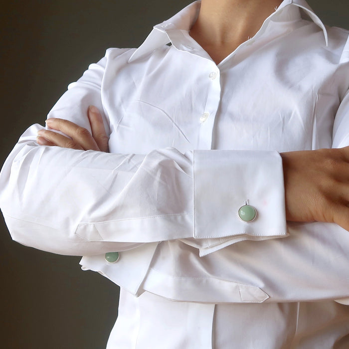 woman with arms crossed wearing white shirt with green cufflinks