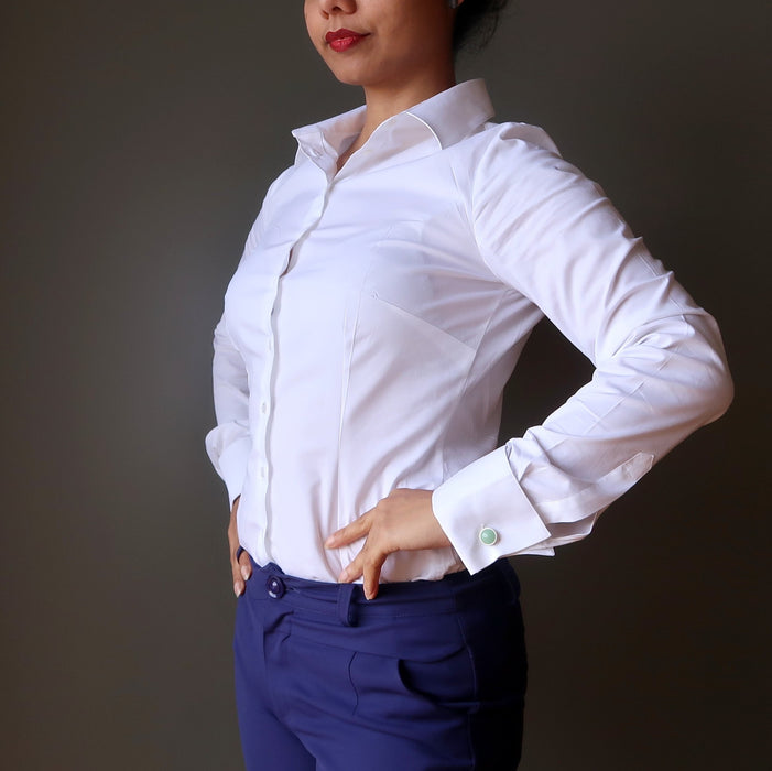 woman with hands on hip \wearing white shirt with green cufflinks