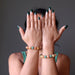 sheila of satin crystals wearing multi colored aventurine stretch bracelets with hands in front of her face