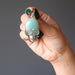 hand holding green aventurine in silver skull pendant