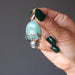 hand holding green aventurine in silver skull pendant