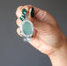 hand holding green aventurine in silver skull pendant showing backside