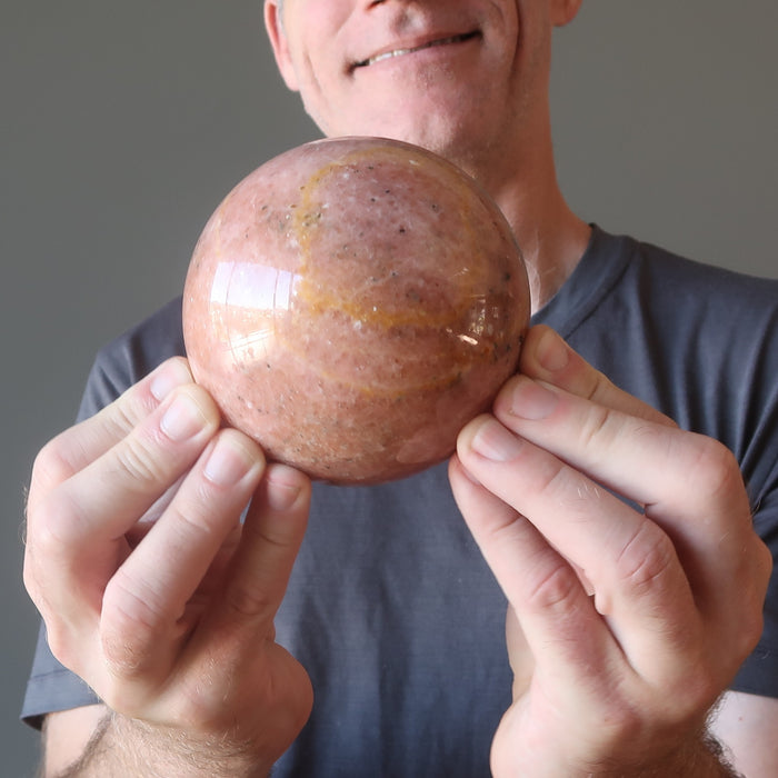male holding pink aventurine sphere