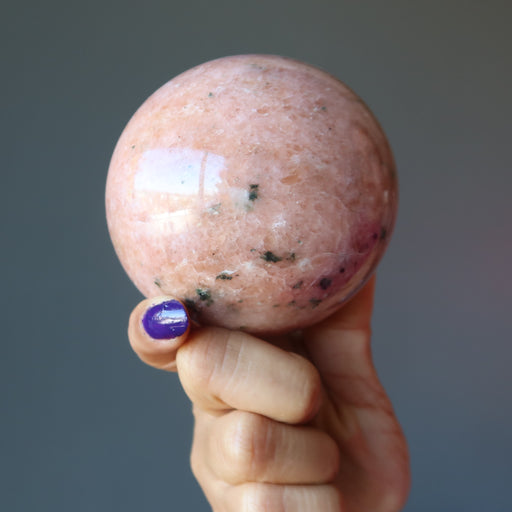hand holding pink aventurine sphere
