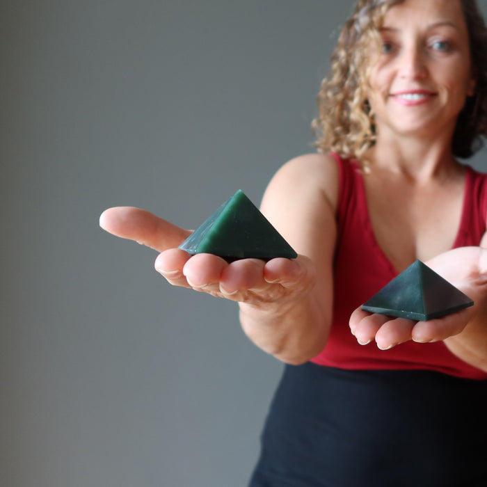woman holding dark green aventurine pyramids