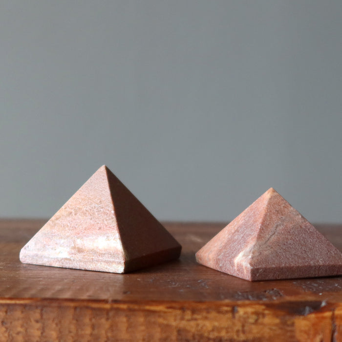 two pink aventurine pyramids on table