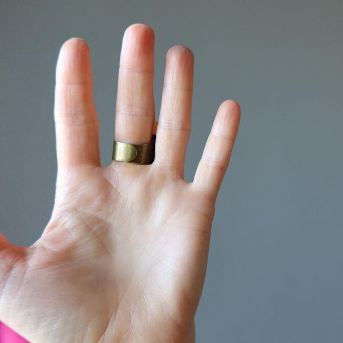 hand wearing a big red orange aventurine oval ring showing the back adjustable bronze metal