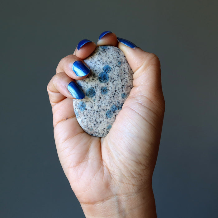 hand holding blue azurite in granite polished oval palm stone