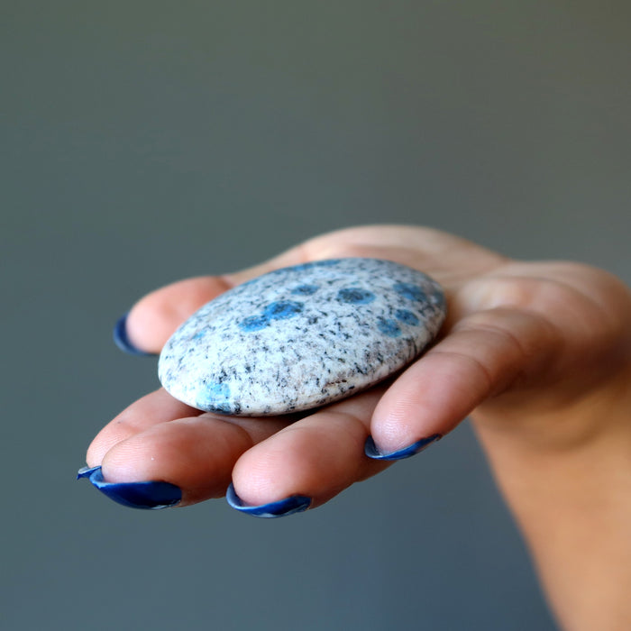 hand holding blue azurite in granite polished oval palm stone