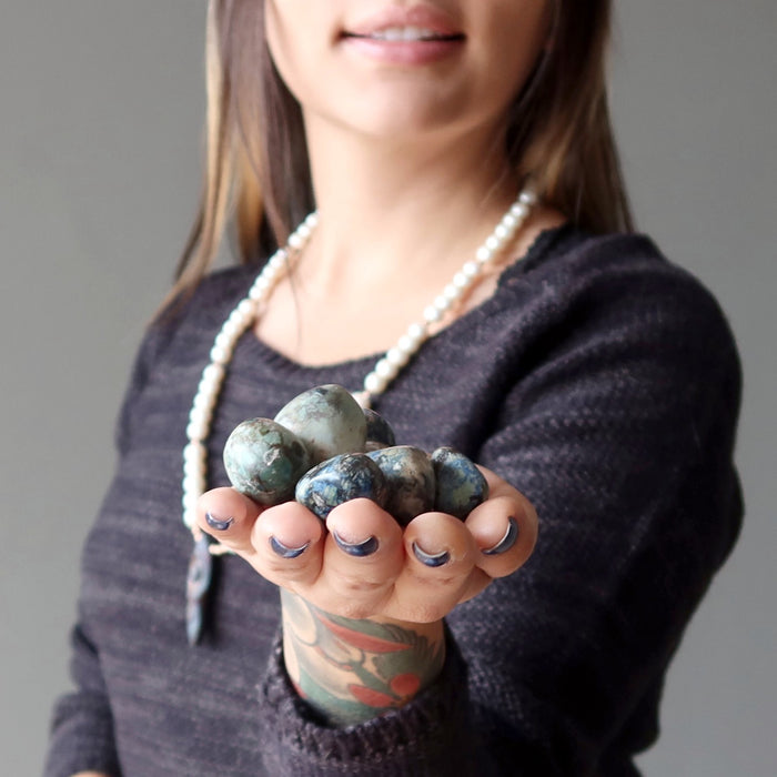woman holding out azurite tumbled stones in her palm
