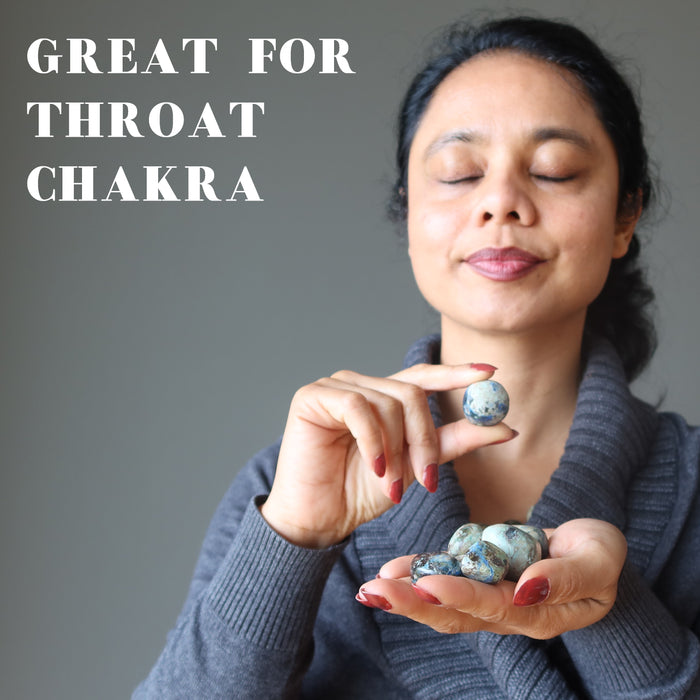 woman holding azurite tumbled stone at her throat chakra