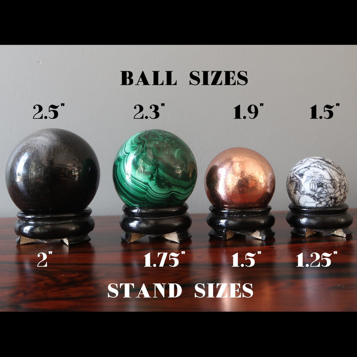a selection of  4 crystal balls on black wood display stand showing their sizes
