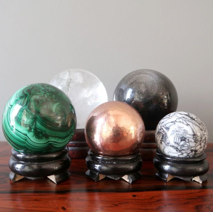 a selection of  5 crystal balls on black wood display stand