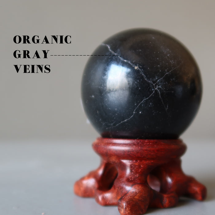 black basalt ball on wood stand showing organic gray veins
