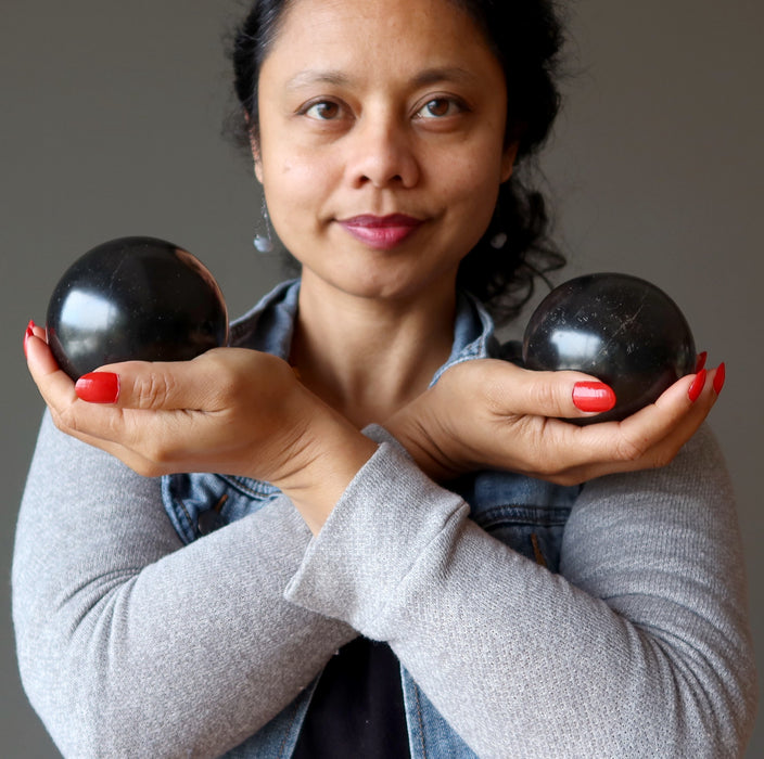 sheila of satin crystals with hands crossed over chest holding black basalt balls