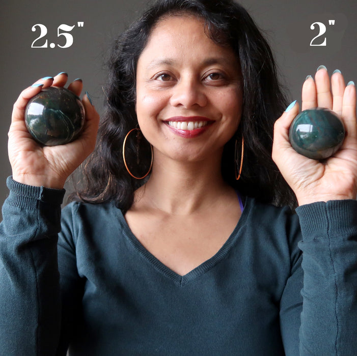 sheila of satin crystals holding two indian bloodstone spheres to show size diffferences