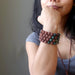 female hand on chin wearing 4 red lava and indian bloodstone round beaded stretch bracelets