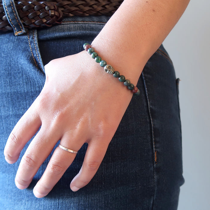 female hand wearing pyrite skull and round bloodstone beaded stretch bracelet