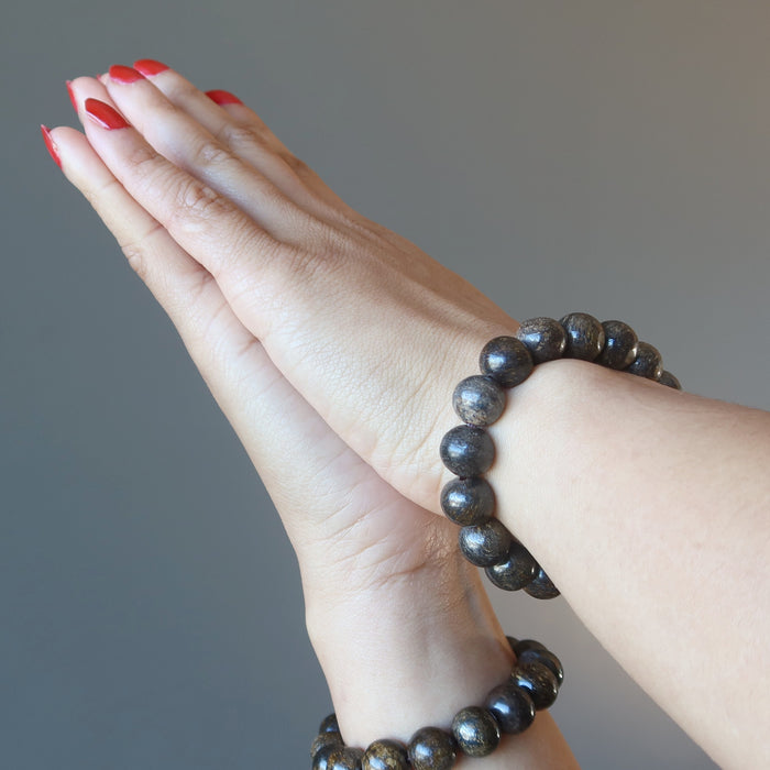 hands clasped wearing bronzite bracelets